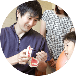 歯列模型を使って親子に説明する歯科医師