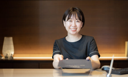 書類を差し出して説明する女性スタッフ