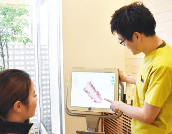 スキャンした歯列の3D画像を患者に見せるスタッフ