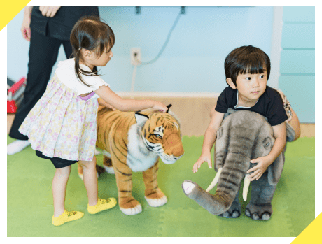 トラとゾウのぬいぐるみで遊ぶ子どもたち