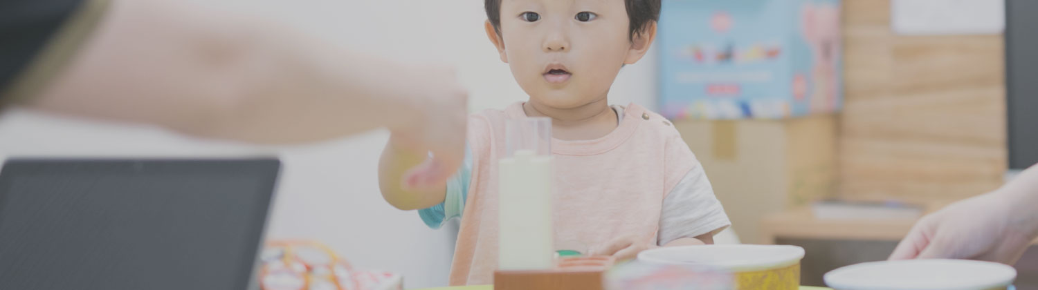 テーブルのおもちゃに手を伸ばす幼児