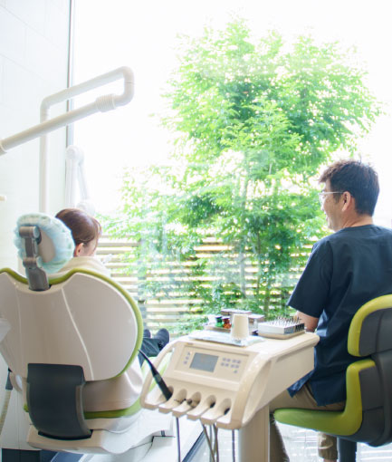診療台の患者と向き合って話す院長