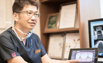 タブレットとモニターの画像を示しながら説明する歯科医師
