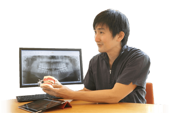 レントゲン画像の前で歯列模型を手にする歯科医師