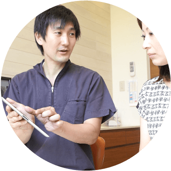 タブレットを手に患者へ説明する歯科医師