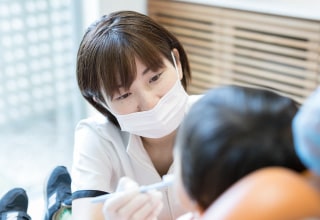マスクを着けて子どもの口元を診るスタッフ