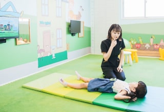 マットに横になる子どもとそばで見守るスタッフ