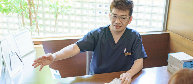 相談者に手で示しながら説明する歯科医師