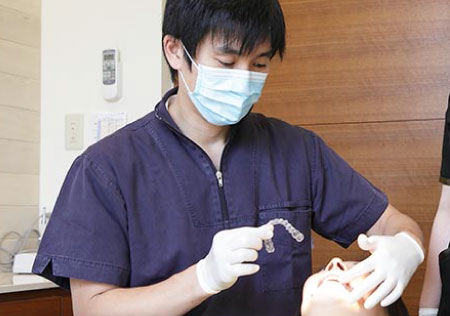 マウスピース型矯正装置を手に患者さんを診療するドクター