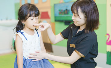 女の子の口元に手を添えて確認するスタッフ